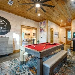 Pool table with a bench in the game room, The Gather House logo on the wall