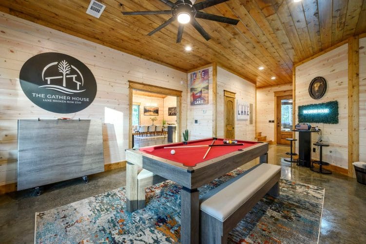 Pool table with a bench in the game room, The Gather House logo on the wall