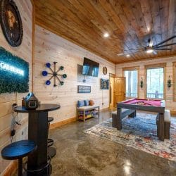 Game room with the pool table at the back and a neon sign on the wall