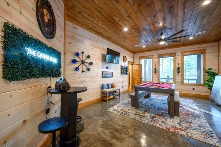 Game room with the pool table at the back and a neon sign on the wall