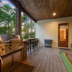 Outdoor kitchen with a stainless grill, bar counter and a putting mat on the deck