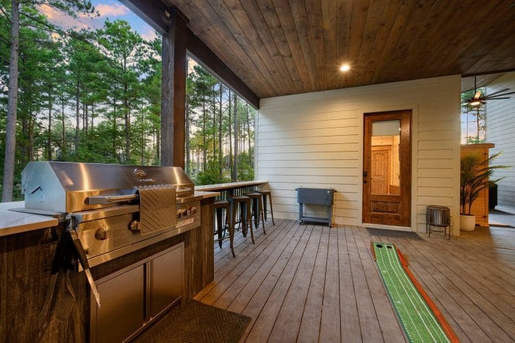 Outdoor kitchen with a stainless grill, bar counter and a putting mat on the deck