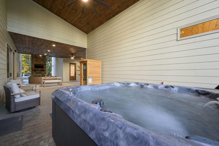 Hot tub on the covered patio with the sauna and seating behind it
