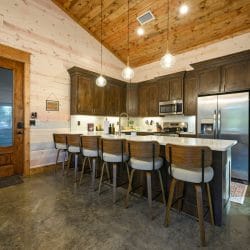 Kitchen with a long island lined with bar stools under pendant lights