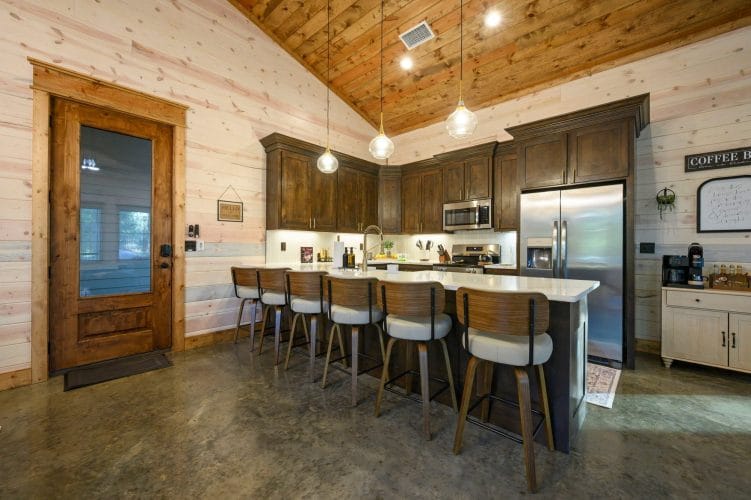 Kitchen with a long island lined with bar stools under pendant lights