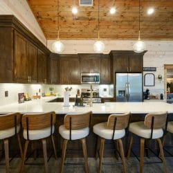 Wide view of the kitchen island, stools and stainless refrigerator