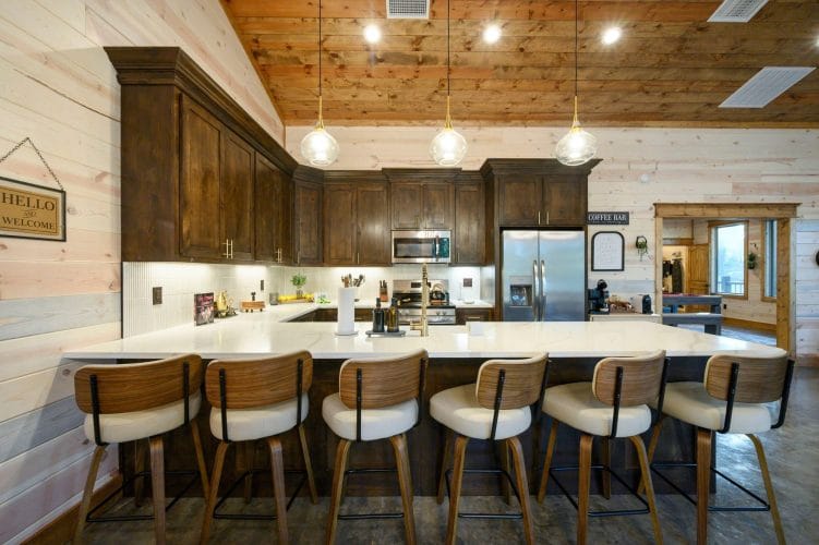 Wide view of the kitchen island, stools and stainless refrigerator
