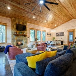 Living room with a navy sectional, stone fireplace and TV under a wood ceiling