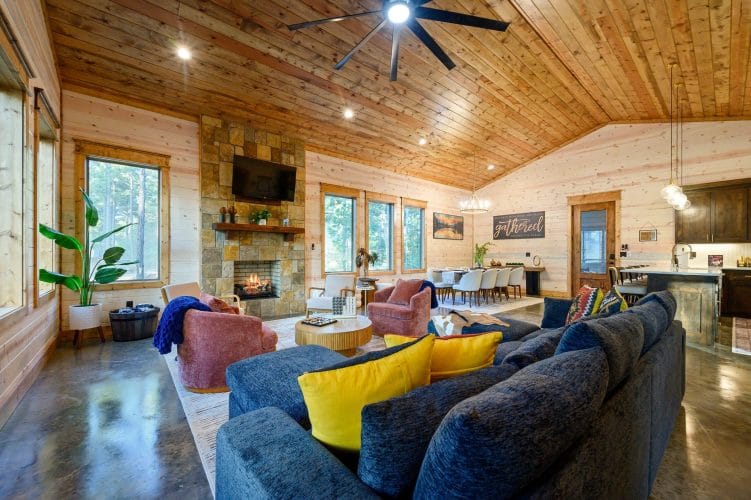 Living room with a navy sectional, stone fireplace and TV under a wood ceiling