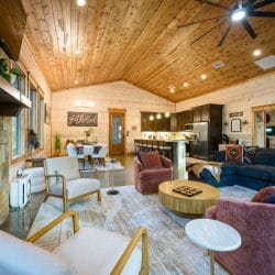 Open living area with a fireplace and armchairs, kitchen and dining beyond