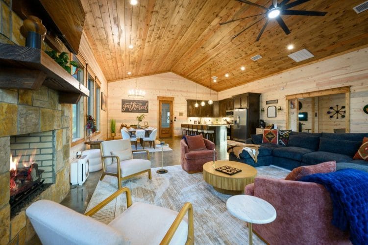 Open living area with a fireplace and armchairs, kitchen and dining beyond
