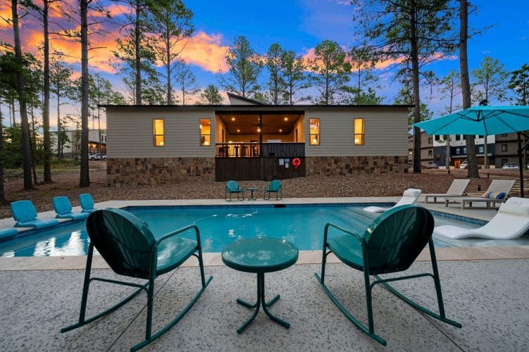 Two green rocking chairs beside the pool at dusk
