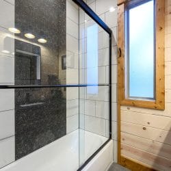 Glass-enclosed tile shower with a patterned dark tile wall