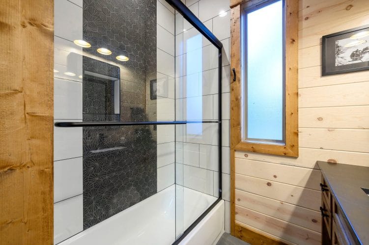Glass-enclosed tile shower with a patterned dark tile wall