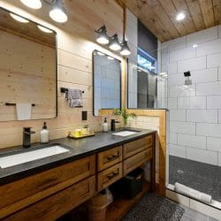 Bathroom vanity with a dark counter, black faucet and a large mirror