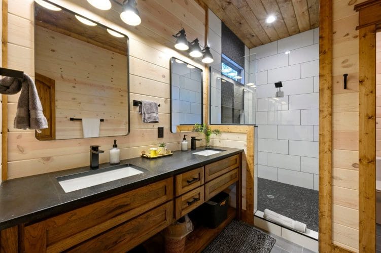 Bathroom vanity with a dark counter, black faucet and a large mirror