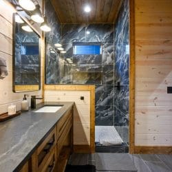 Shower wall in dark marbled tile next to the vanity