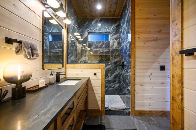 Shower wall in dark marbled tile next to the vanity