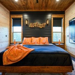 Bed headboard area with three orange pillows and a blue blanket