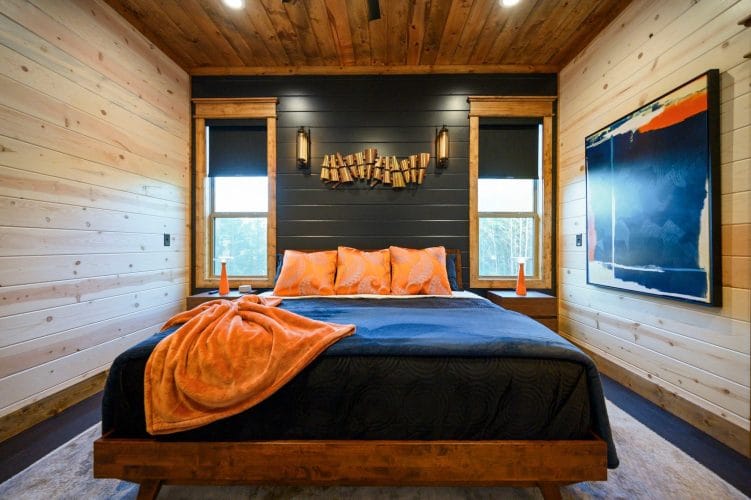 Bed headboard area with three orange pillows and a blue blanket
