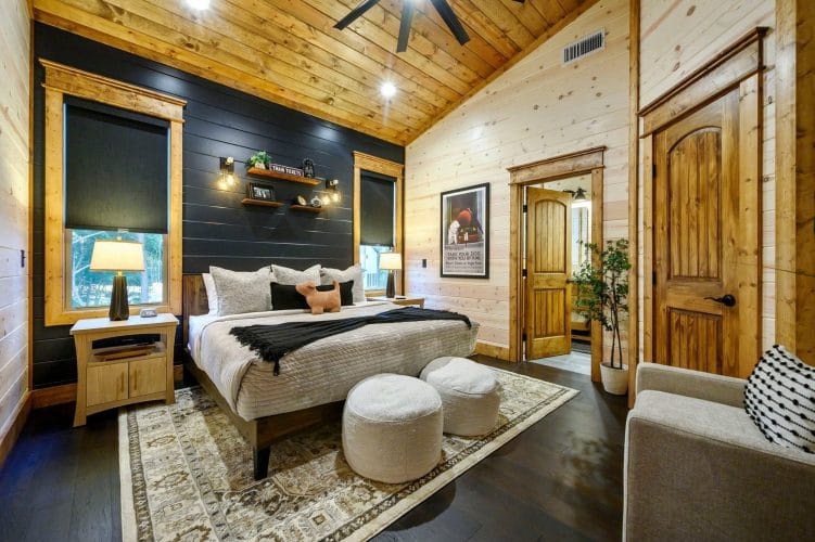 Bed with gray bedding and a railroad poster on the wall, with a small stuffed dog on the pillow