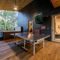 Ping pong table on the covered patio with a giant Connect Four game and the cabin door behind it
