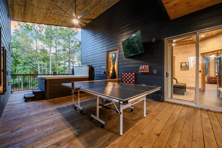 Ping pong table on the covered patio with a giant Connect Four game and the cabin door behind it