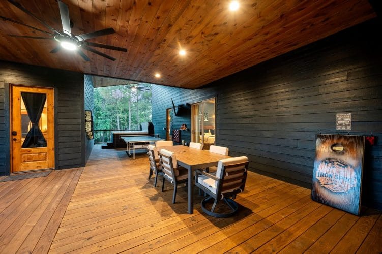 Covered patio dining table with ping pong table, outdoor TV and a bedroom door behind