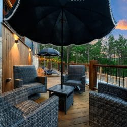 Deck with a scalloped patio umbrella, woven chairs and string lights