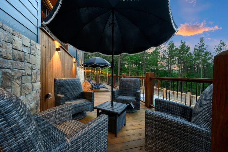 Deck with a scalloped patio umbrella, woven chairs and string lights