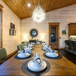 Long wooden dining table set with plates and folded napkins