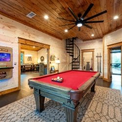Red-felt pool table with a black spiral staircase and the laundry closet behind it