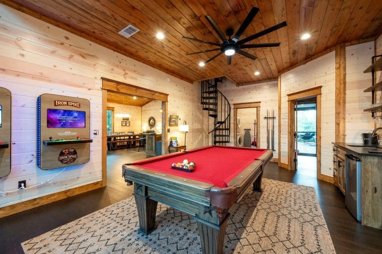 Red-felt pool table with a black spiral staircase and the laundry closet behind it