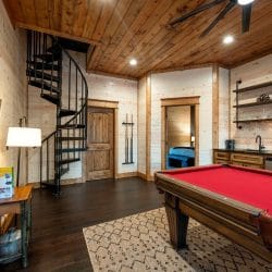 Pool cue rack on the wall beside a wood door and the spiral staircase