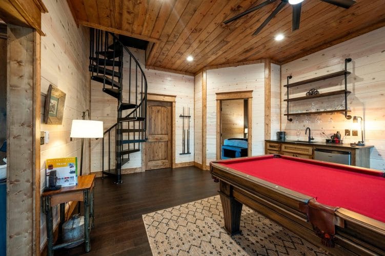 Pool cue rack on the wall beside a wood door and the spiral staircase