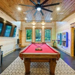 Pool table under three windows with chairs along the wall