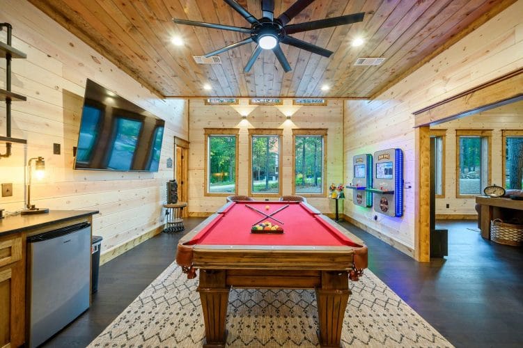 Pool table under three windows with chairs along the wall