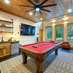 Pool table with a wall-mounted TV above it and a wood door beside
