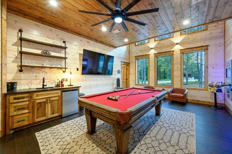 Pool table with a wall-mounted TV above it and a wood door beside