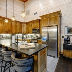 Kitchen with wood cabinets, stainless refrigerator and microwave, and a dark island counter