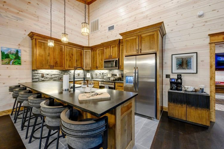Kitchen with wood cabinets, stainless refrigerator and microwave, and a dark island counter