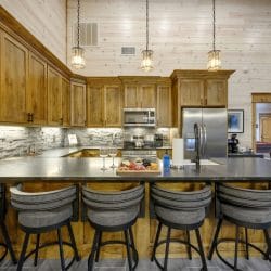 Stainless range and microwave with a stone tile backsplash and a charcuterie board on the island