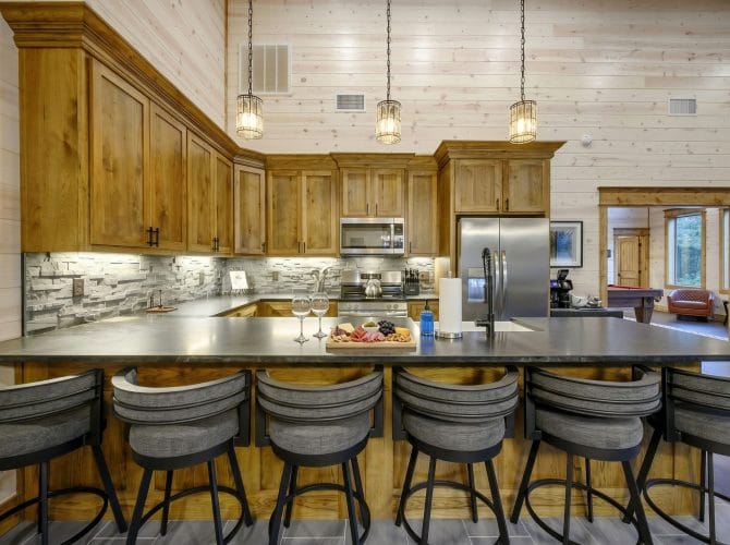 Stainless range and microwave with a stone tile backsplash and a charcuterie board on the island