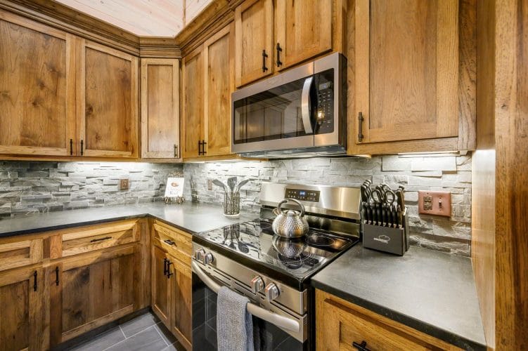Stovetop, range hood and kitchen utensils against a light stone backsplash