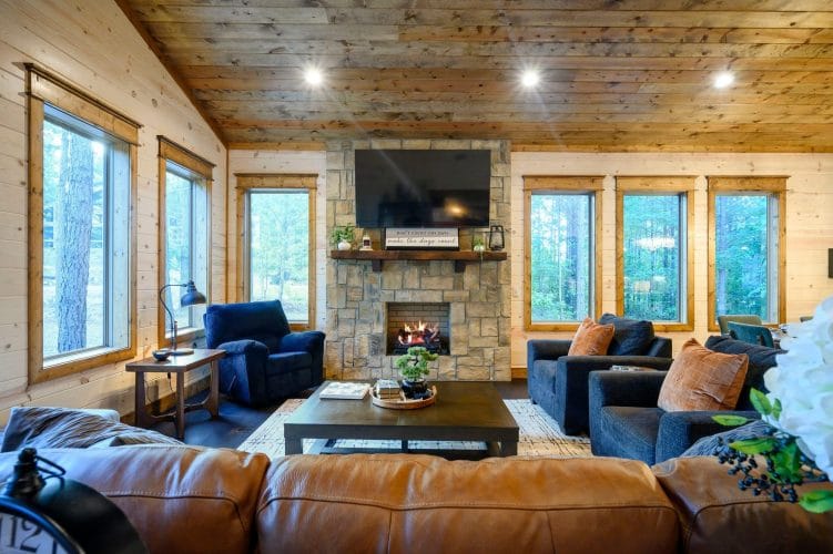 Stone fireplace with a lit gas log, wood mantel and TV above it