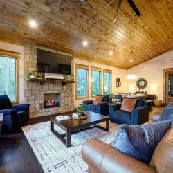 Living room seating facing the stone fireplace, with windows along the wall
