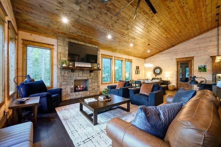 Living room seating facing the stone fireplace, with windows along the wall