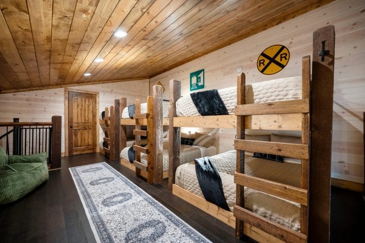 Bunk beds in the loft with a wooden ladder and dark throw blankets