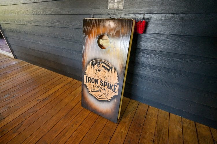 Cornhole board with the Iron Spike Lodge logo