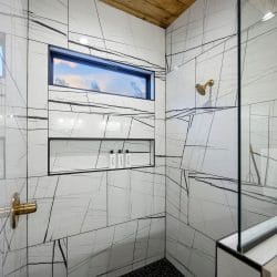 Shower with veined white tile and a window above